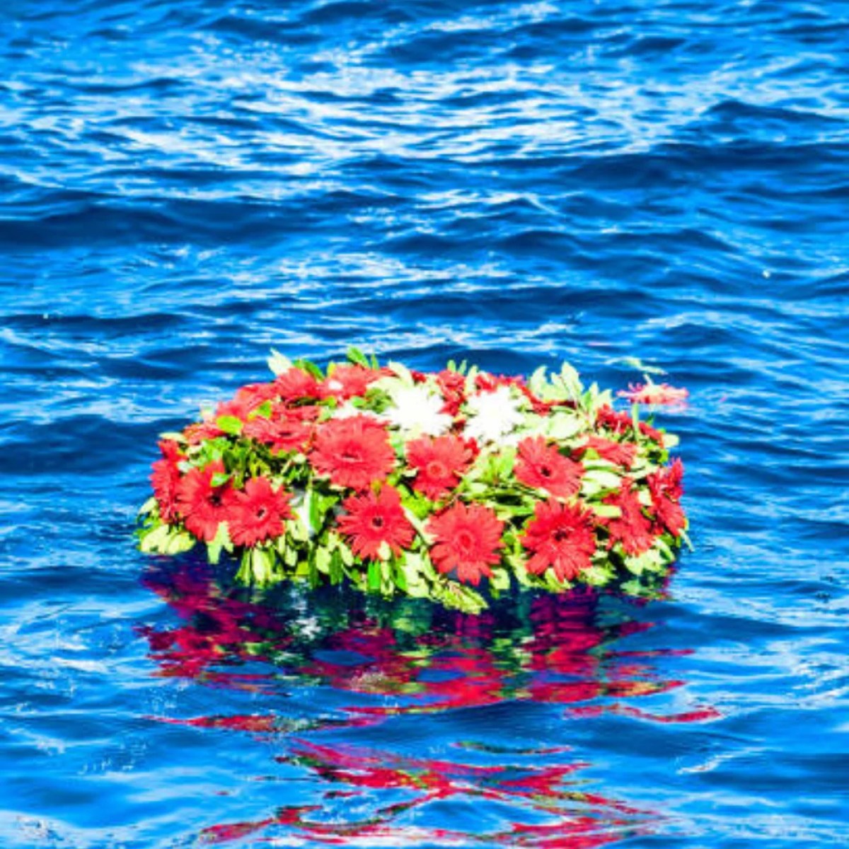 A colorful flower wreath floating on blue water.