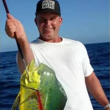 Man holding a large fish and a child holding a smaller fish, both smiling outdoors.